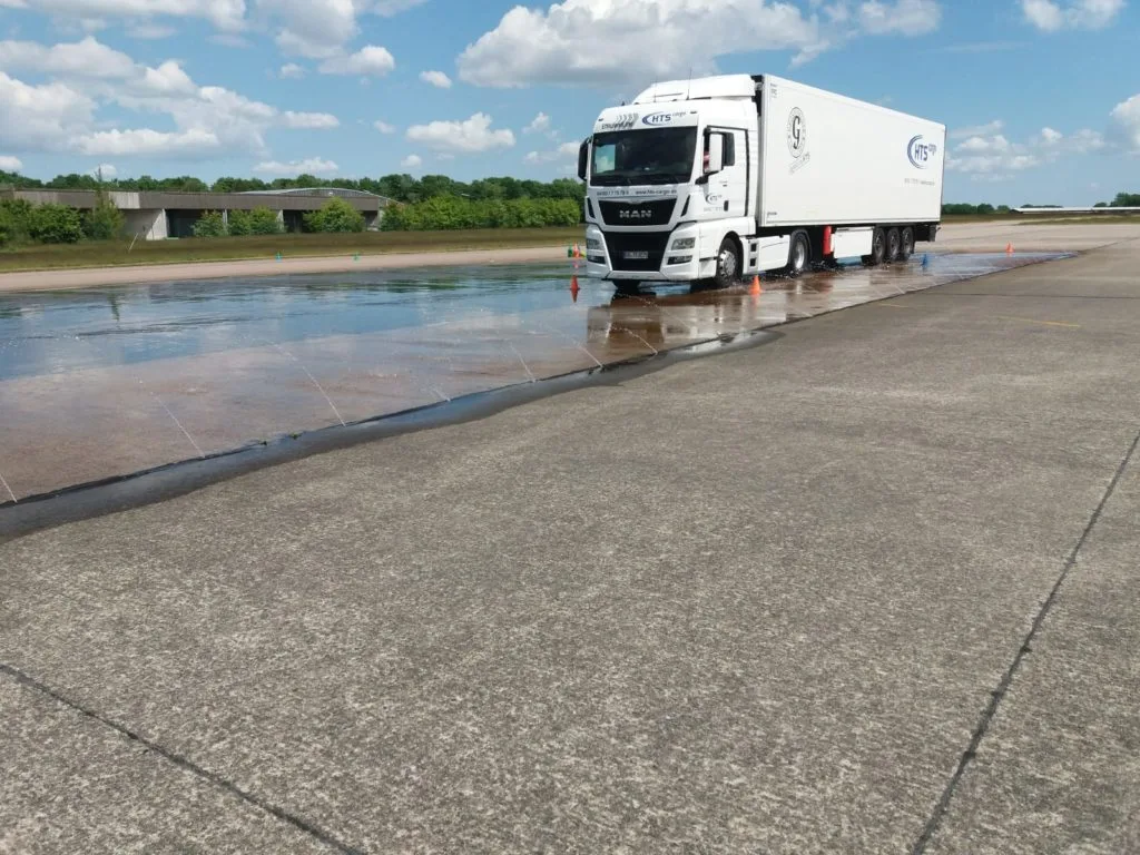 Sattelzug von HTS cargo auf einer nassen Trainingsfläche.